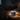 Jar of Aribella Moonlit Magnesium Cream on a bedside table with a person lying in bed in the background
